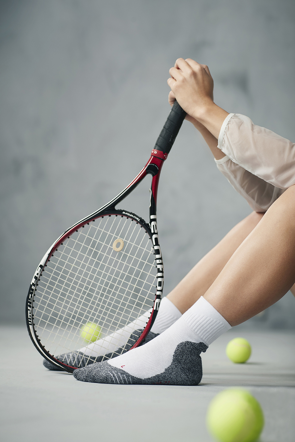 Een foto van een mens met een tennisracket in zijn hand, die ook sportsokken aan heeft